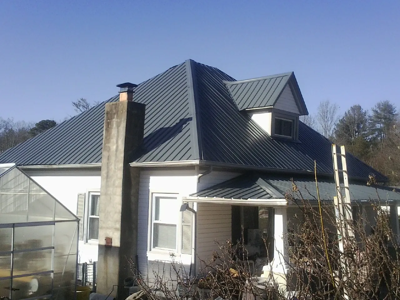 Dark blue standing seam metal roof on a white farmhouse with dormer — Slate & Tile Roof Repair by Roofing Brothers in Parkesburg