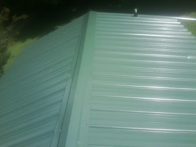 New green metal panels meeting at the ridge of a roof — Flat Roof Repair work by our crew in Parkesburg