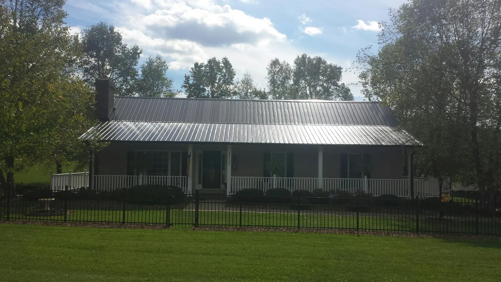 Gray metal roof on a brick ranch with a full width front porch — Gutter Guard Installation work by our crew in Parkesburg