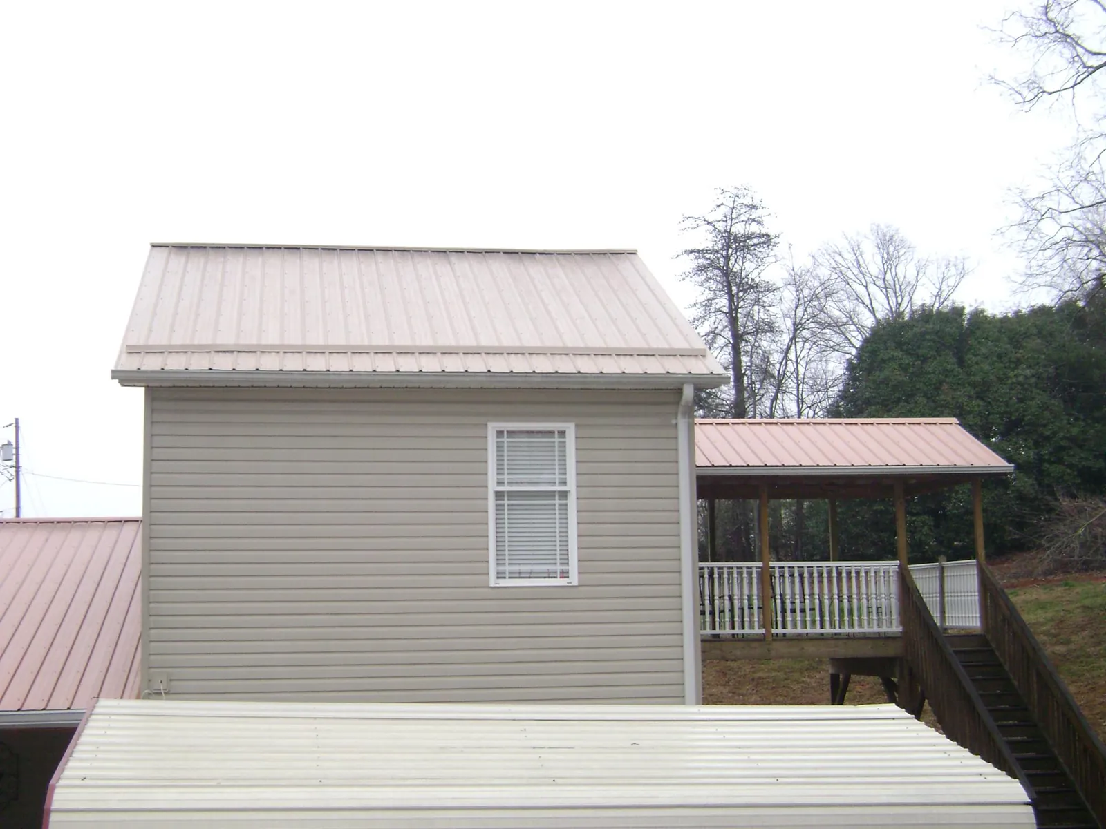 Tan metal roofs on a two story addition and attached porch, from a Roof Replacement job in Parkesburg