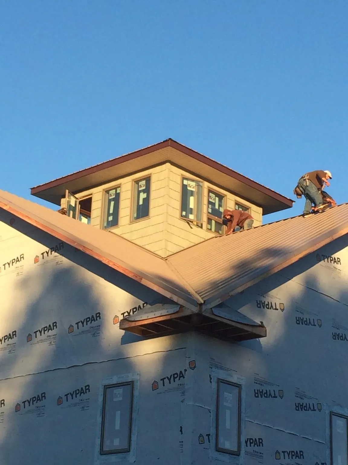 Roofers working around a rooftop cupola on a new metal roof at sunset — Roof Waterproofing in Parkesburg by Roofing Brothers
